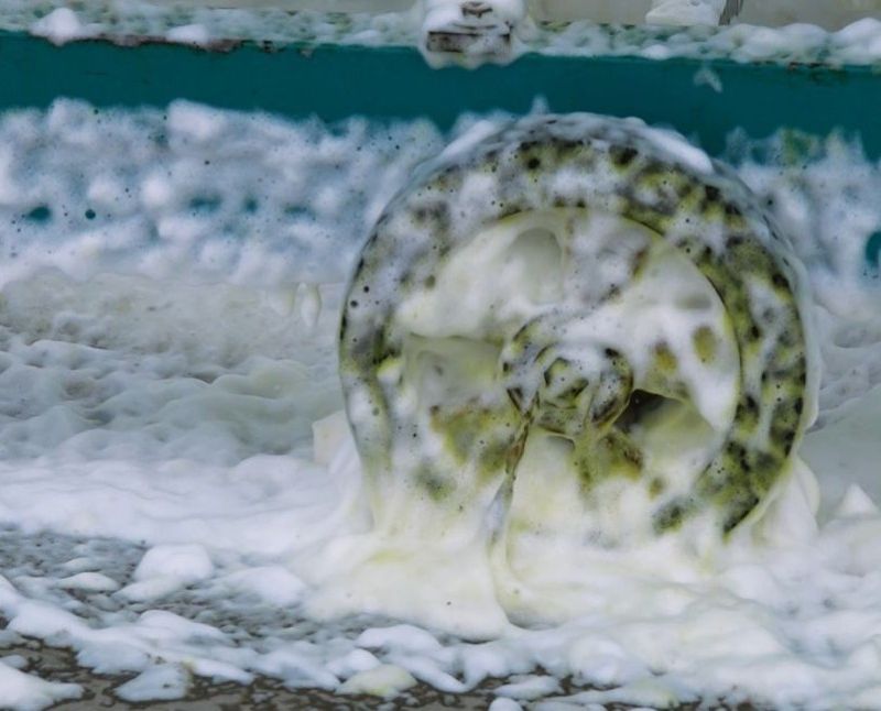 Foamy water with a wheel submerged, possibly in a pool or pond.